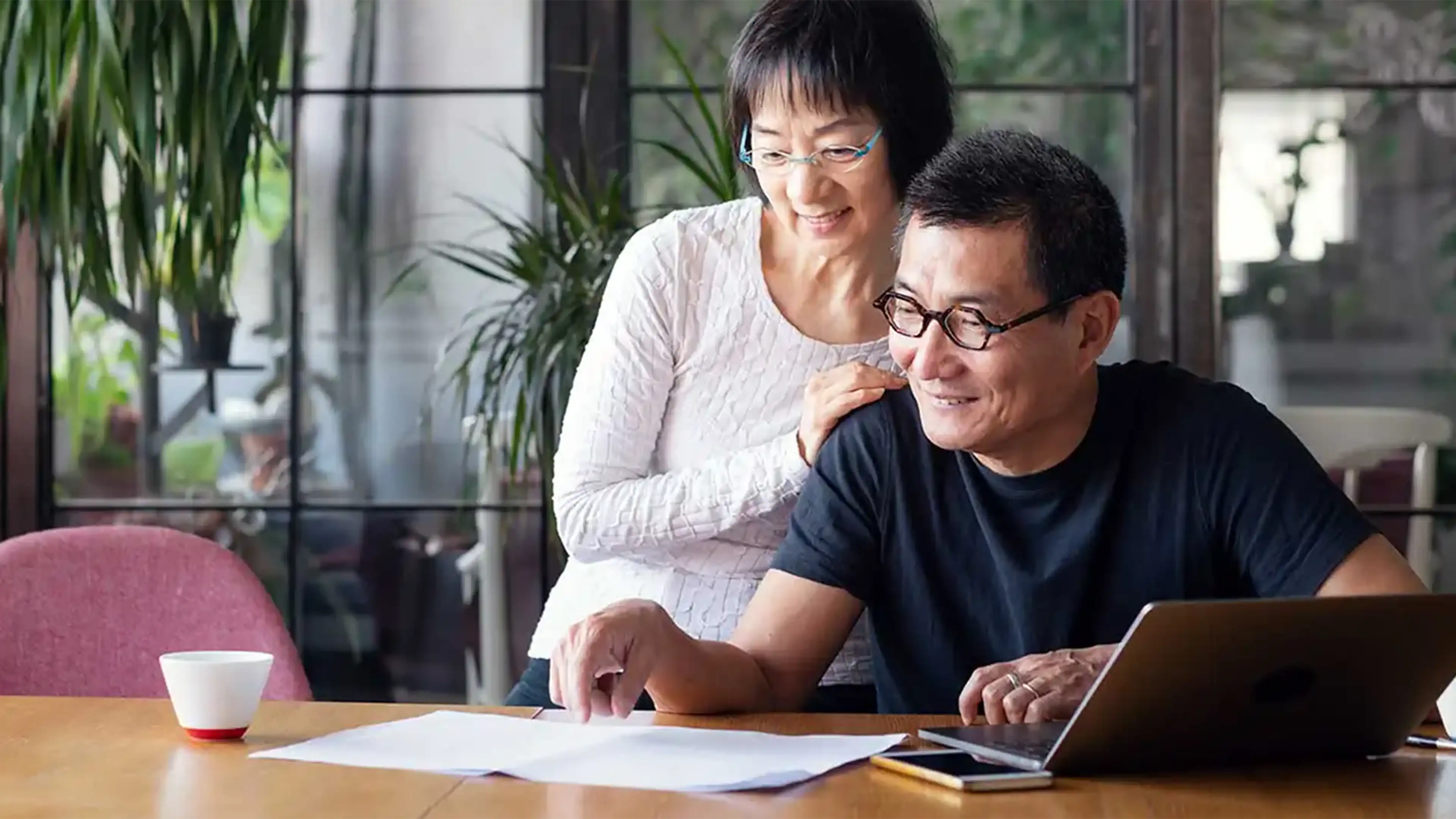 happy couple looking at papers phone and laptop